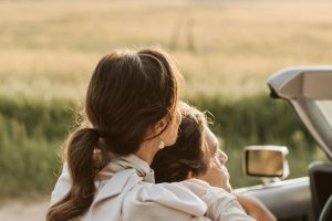 A couple in a convertible embraces during a scenic countryside drive at sunset.